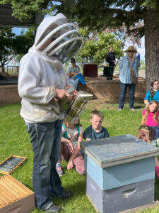 Beekeeper shows children how a bee hive smoker works.