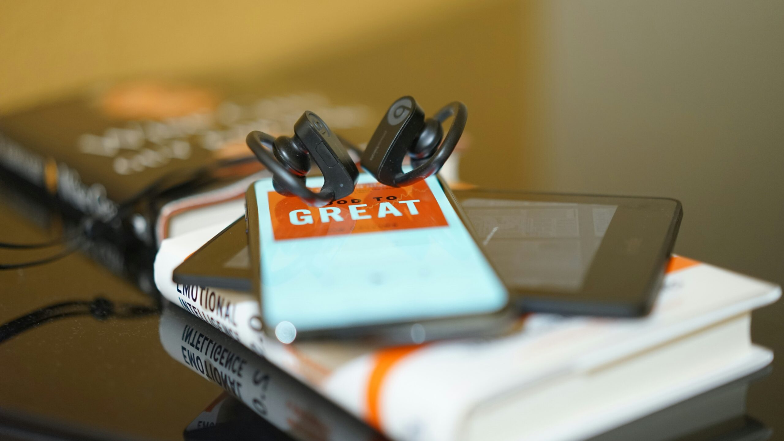 iphone with ear buds on top of an eReader and book