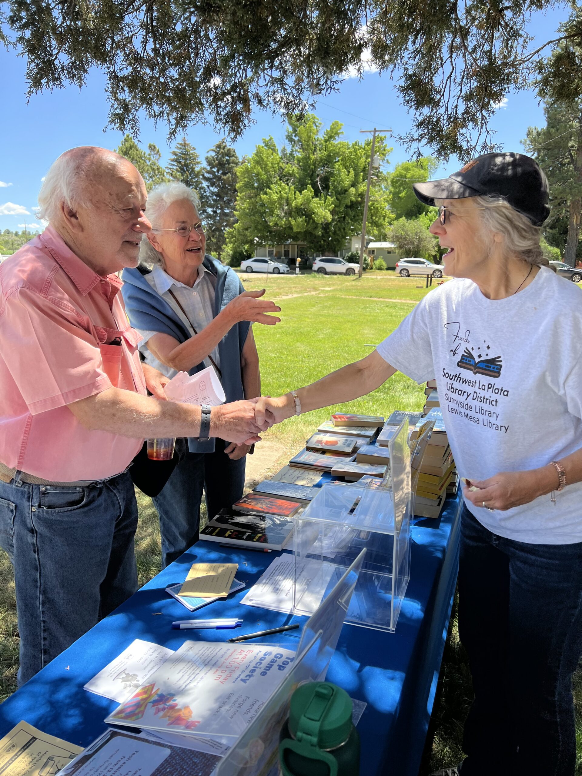 Two people shaking hands while another looks on. 